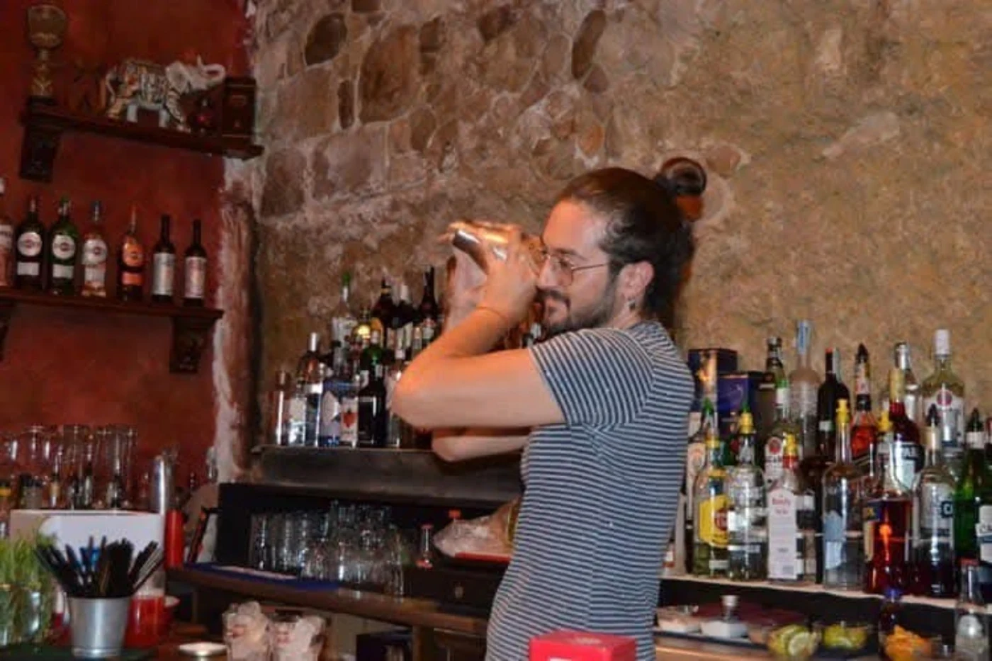 Mario prepara un cocktail con lo shaker dietro il bancone in pietra